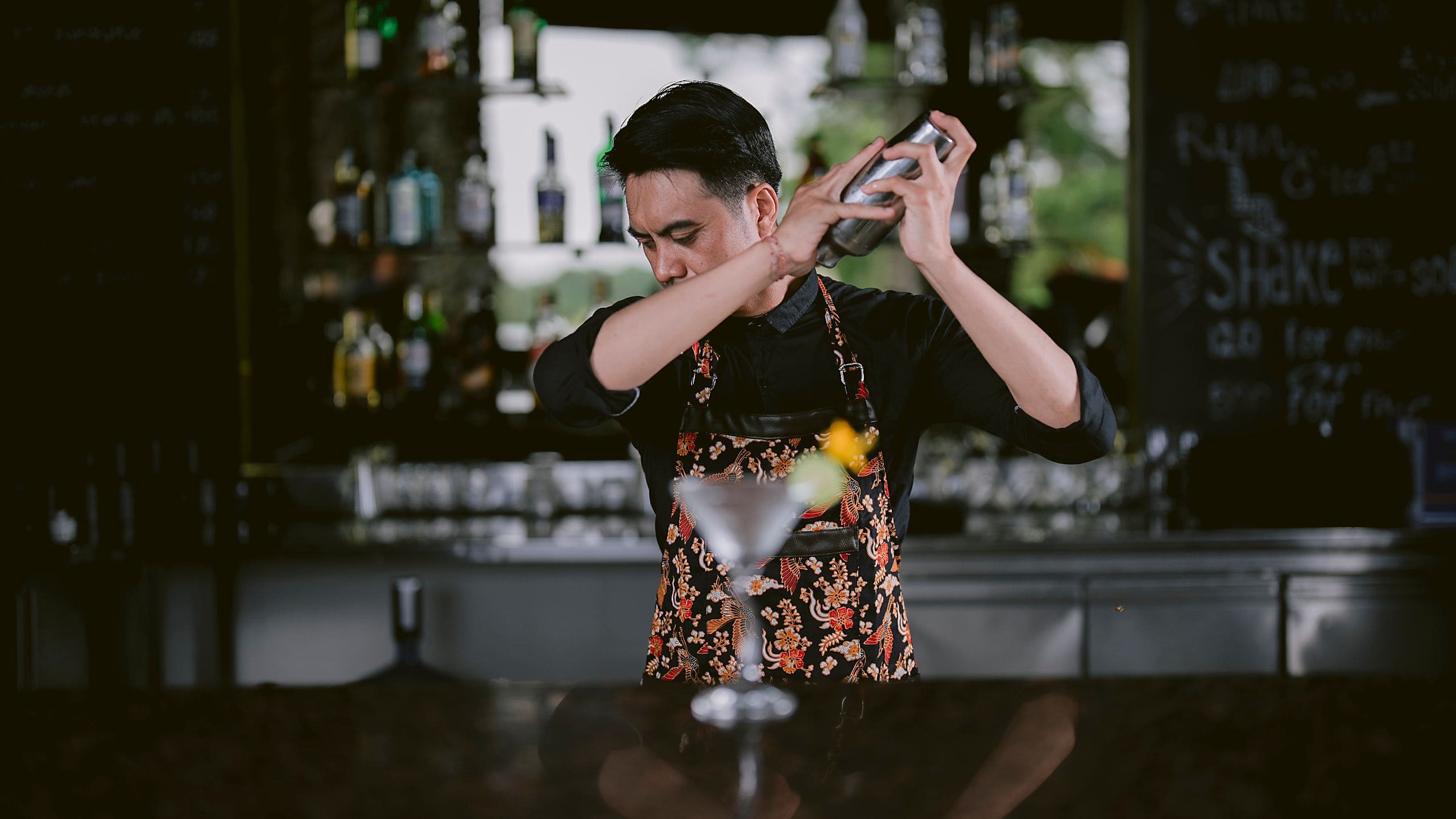 A bartender shakes a cocktail behind the bar counter at Cabana Lounge