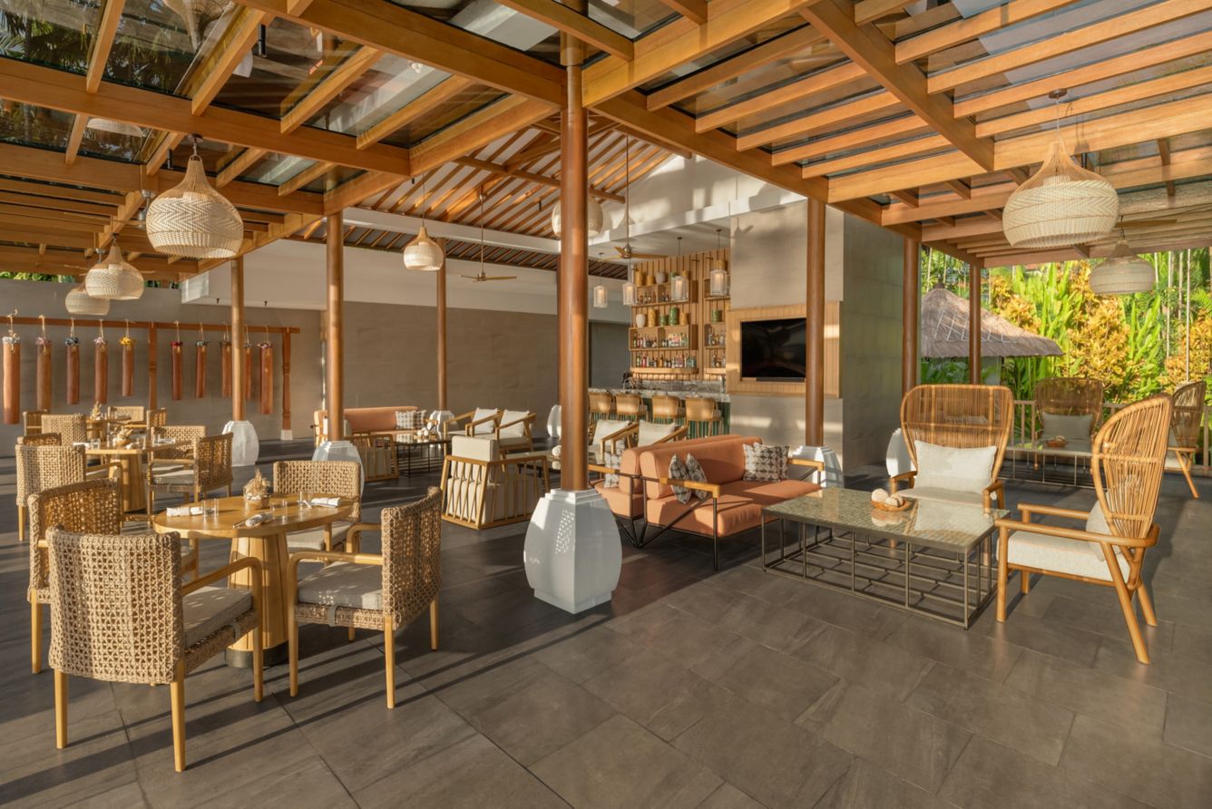 Furnitur rotan dan lounge Kulkul Beach House dalam cahaya pagi yang hangat