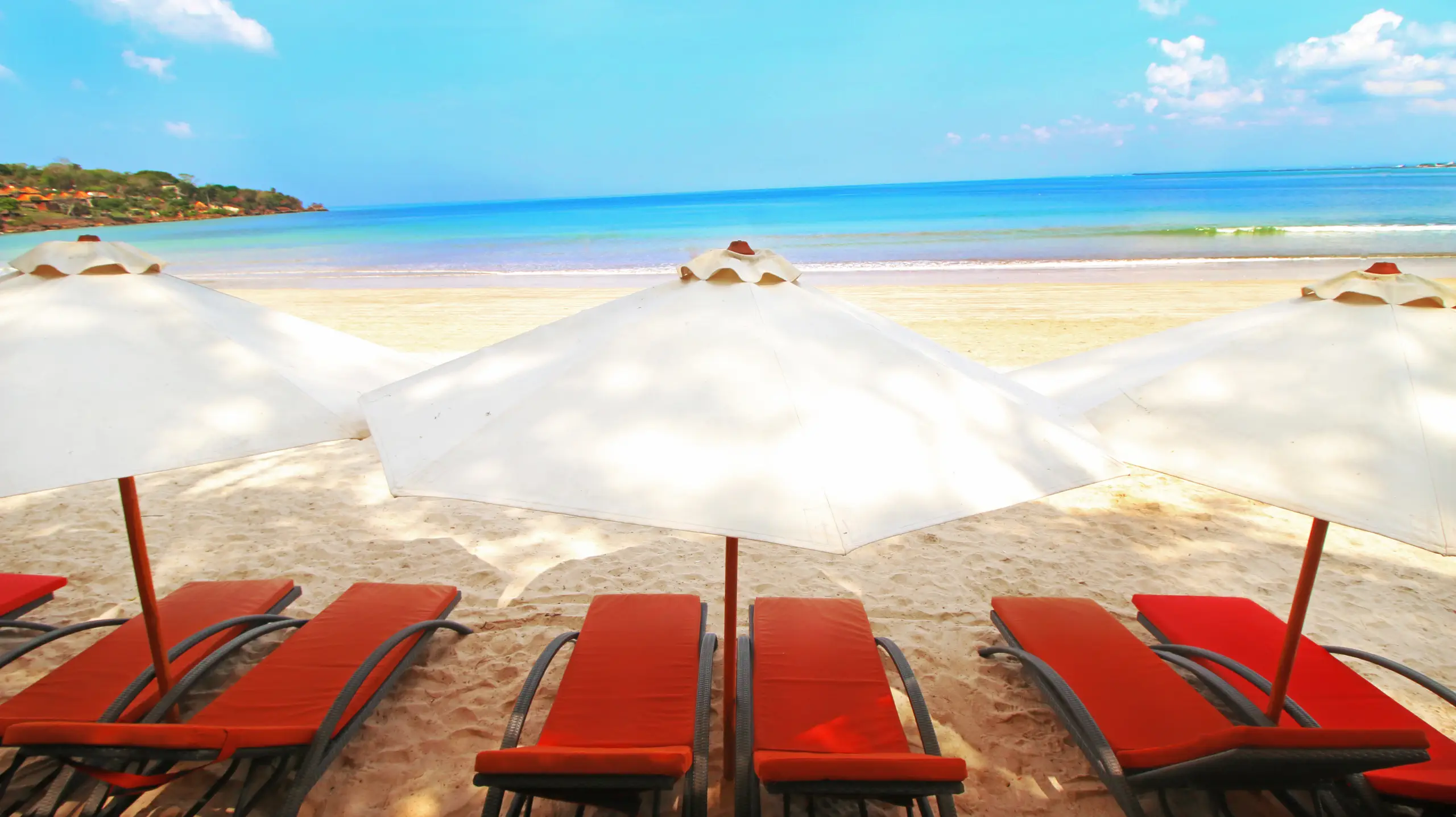 Loungers at Kupu Kupu Jimbaran Beach Club under a bright sky