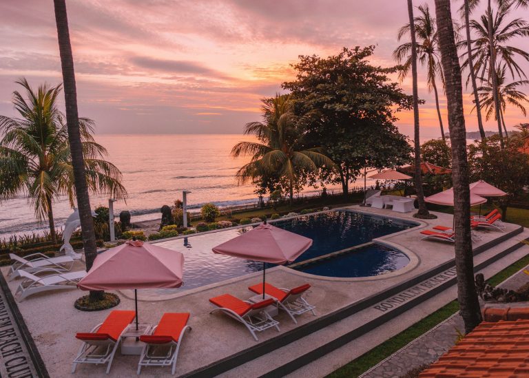 Pool and ocean at Bondalem Beach Club under a sunset sky