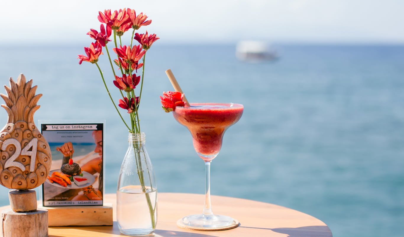 Red drink on a beachfront table at Penida Colada