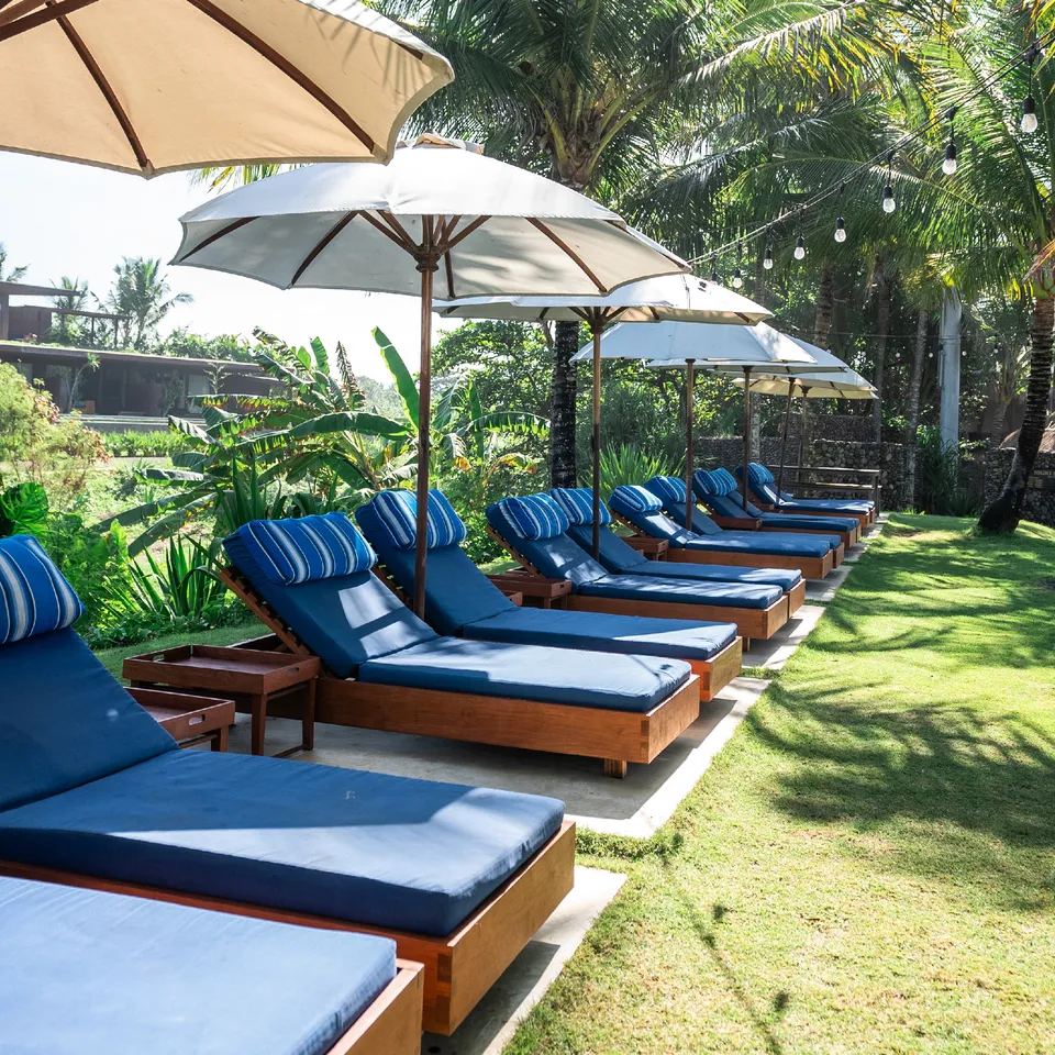 Sun lounger berjajar di lawn Komune Beach Club Keramas