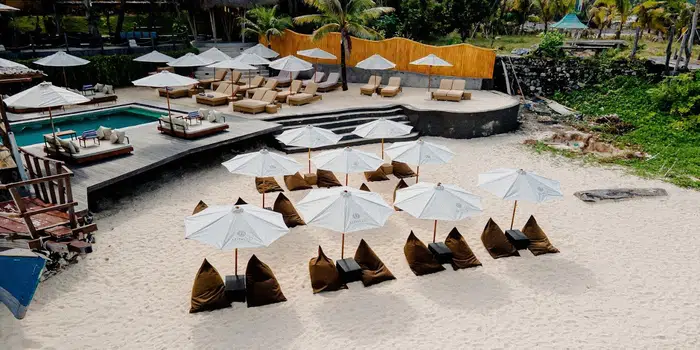 Wide view of the beach, pool and parasol seating at Minoo Beach Club.